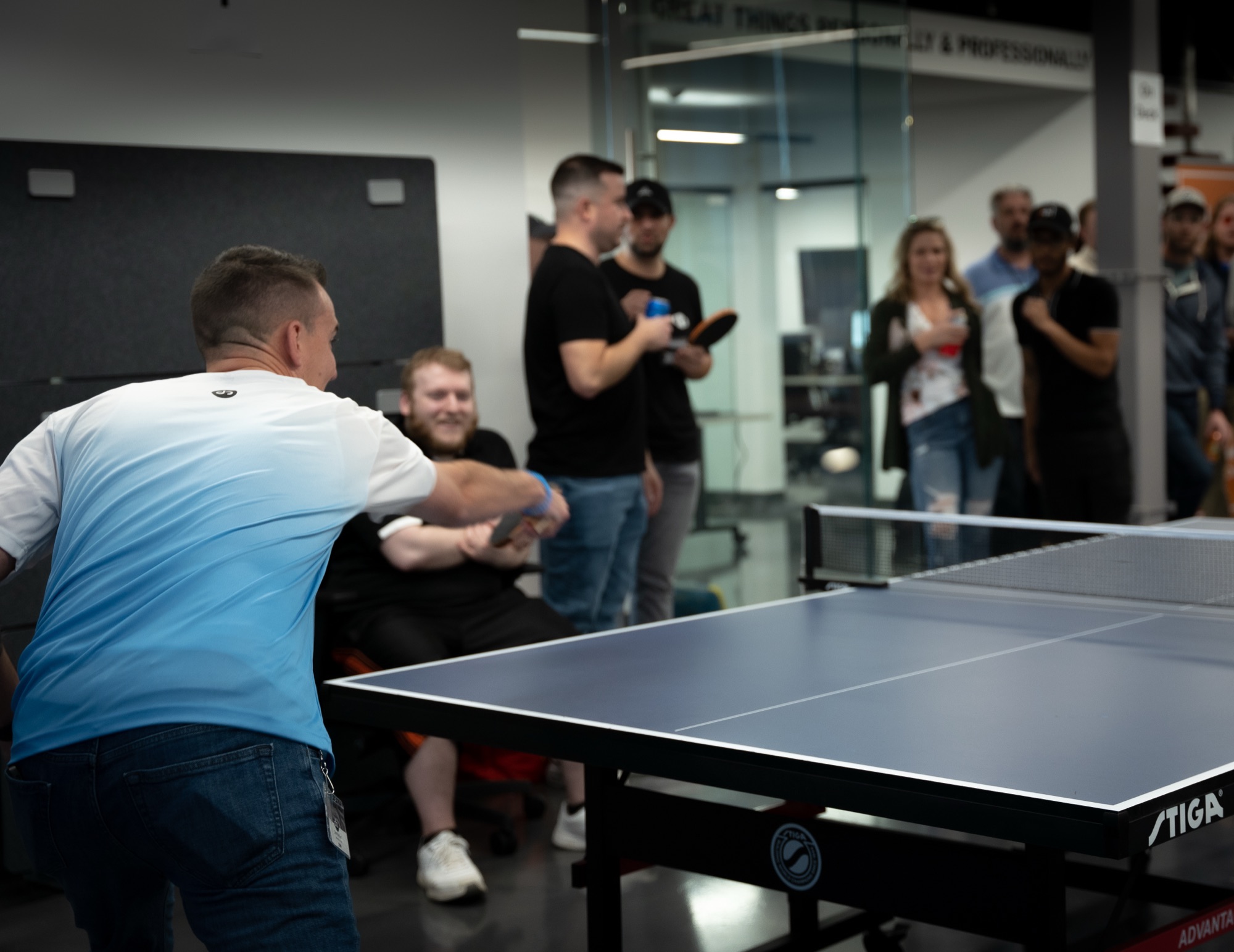 A ping pong match in progress at the Jahnel Group office with colleagues watching